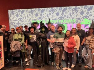 Group at a Pride Movie Night gathered around Kitana Sanchez as Elphaba, the Wicked witch, at Alamo Drafthouse.