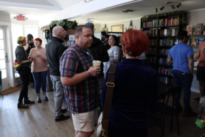 People mingle and chat over drinks among bookshelves at Pride Corpus Christi's February social at The Cookie Plot.