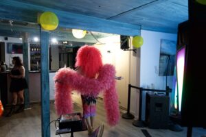 Brigitte Bandit in feather boa performs at a Pride event inside The Loft bar.