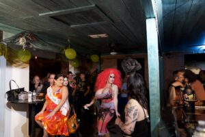 Brigitte Bandit engages the crowd at an indoor Pride event at The Loft as guests watch and mingle.