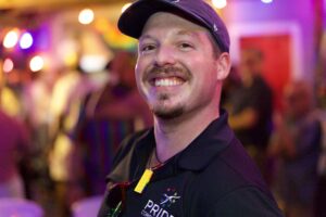 Robert Kymes in a Pride Corpus Christi polo and cap at a colorful kickoff event.
